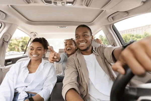 A family smiling while driving safely in their modern white car